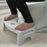 Space-saving folding toilet stool in white, with non-slip grip.